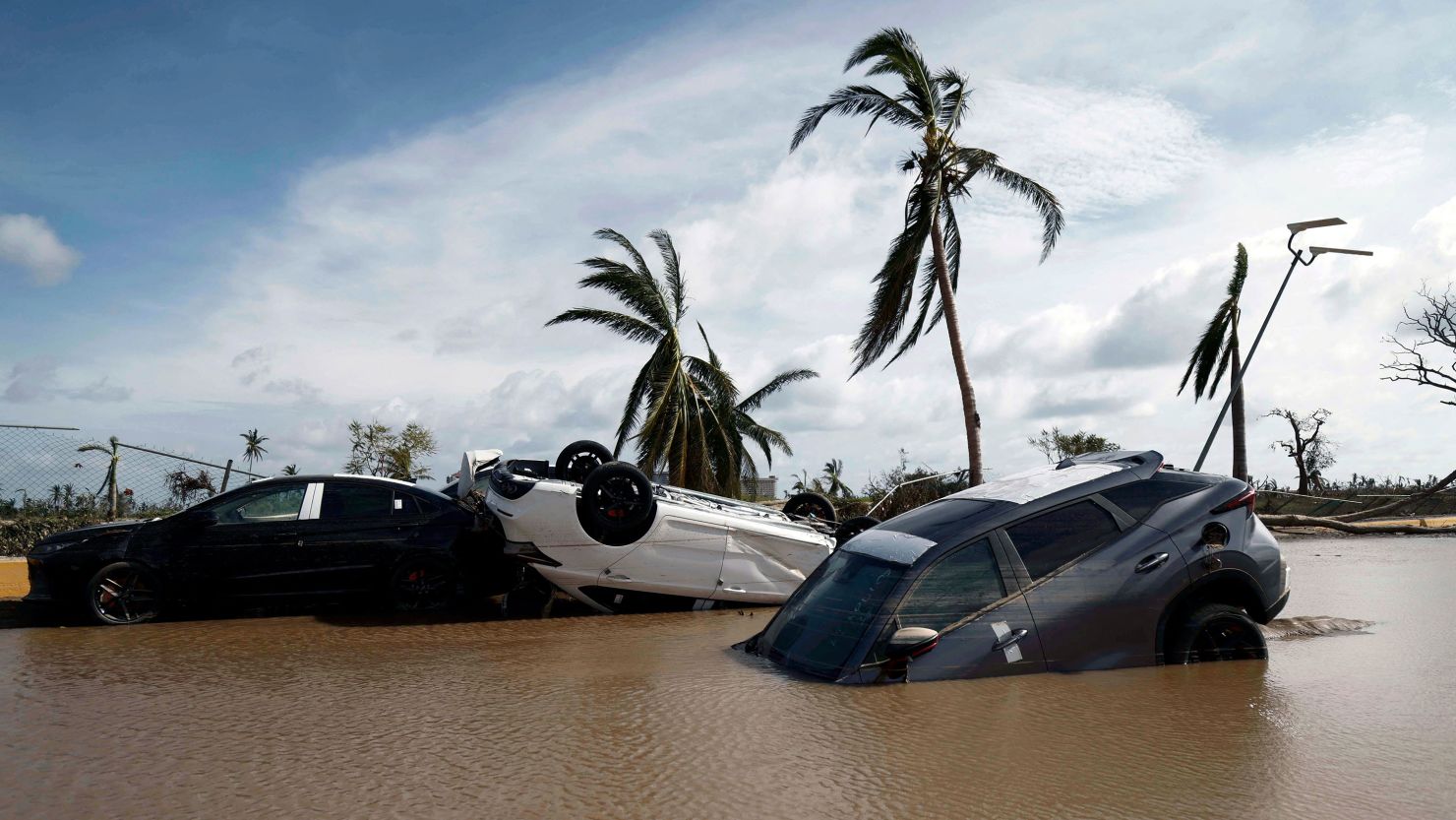 TOPSHOT - Cars lay partially under water in the aftermath of hurricane Otis at "Zona Diamante" in Acapulco, Guerrero State, Mexico, on October 27, 2023. Airlines began to evacuate tourists from Mexico's beachside city of Acapulco on Friday after a scale-topping Category 5 hurricane left a trail of destruction and at least 27 people dead, authorities said on October 27, 2023. (Photo by RODRIGO OROPEZA / AFP) (Photo by RODRIGO OROPEZA/AFP via Getty Images)