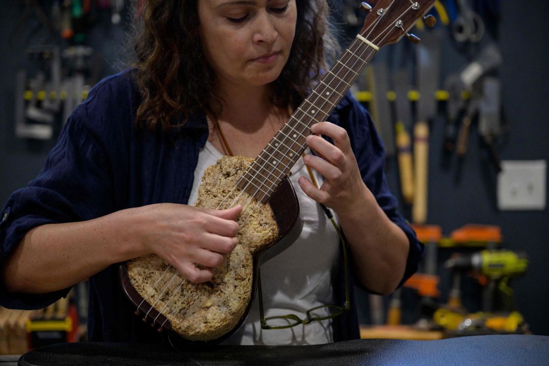 French luthier Rachel Rosenkrantz plays a ukulele made using mycelium in her studio on June 21, 2023, in Providence, Rhode Island. Leave mushroom spores in a mold for a couple weeks and they'll bloom into a puffy material akin to brie, says Rosenkrantz, a sustainability-minded guitar-maker innovating with bio-materials. Once her mycelium, the root-like structure of fungus that produces mushrooms, mimics the rind of a soft-ripened cheese Rosenkrantz dehydrates it into a lightweight, biodegradable building material -- in this case, a guitar-body. (Photo by ANGELA WEISS / AFP) (Photo by ANGELA WEISS/AFP via Getty Images)