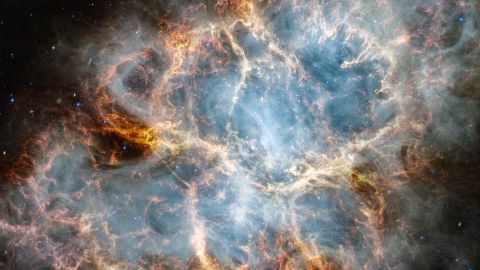 NASA's James Webb Space Telescope has gazed at the Crab Nebula in the search for answers about the supernova remnant's origins. Webb's NIRCam (Near-Infrared Camera) and MIRI (Mid-Infrared Instrument) have revealed new details in infrared light.

Similar to the Hubble optical wavelength image released in 2005, with Webb the remnant appears comprised of a crisp, cage-like structure of fluffy red-orange filaments of gas that trace doubly ionized sulfur (sulfur III). Among the remnant's interior, yellow-white and green fluffy ridges form large-scale loop-like structures, which represent areas where dust particles reside.