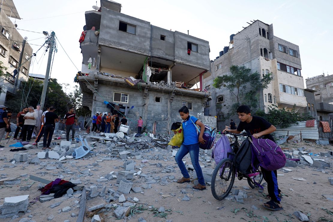 Young Palestinians walk in front of a damaged house in the aftermath of Israeli strikes in Khan Younis, Gaza, on October 30, 2023.