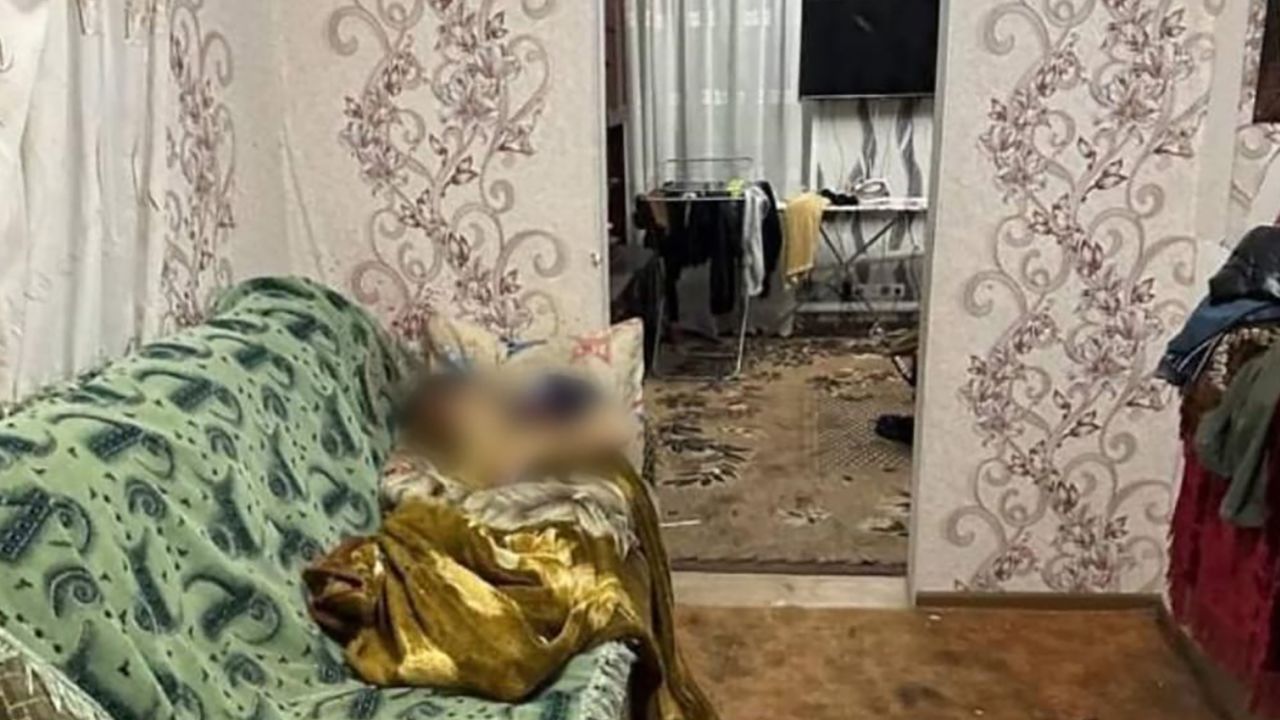A person blurred out lying on a sofa. The image is taken in the home of the family that was shot dead in in the town of Volnovakha in Ukraine's occupied Donetsk region.