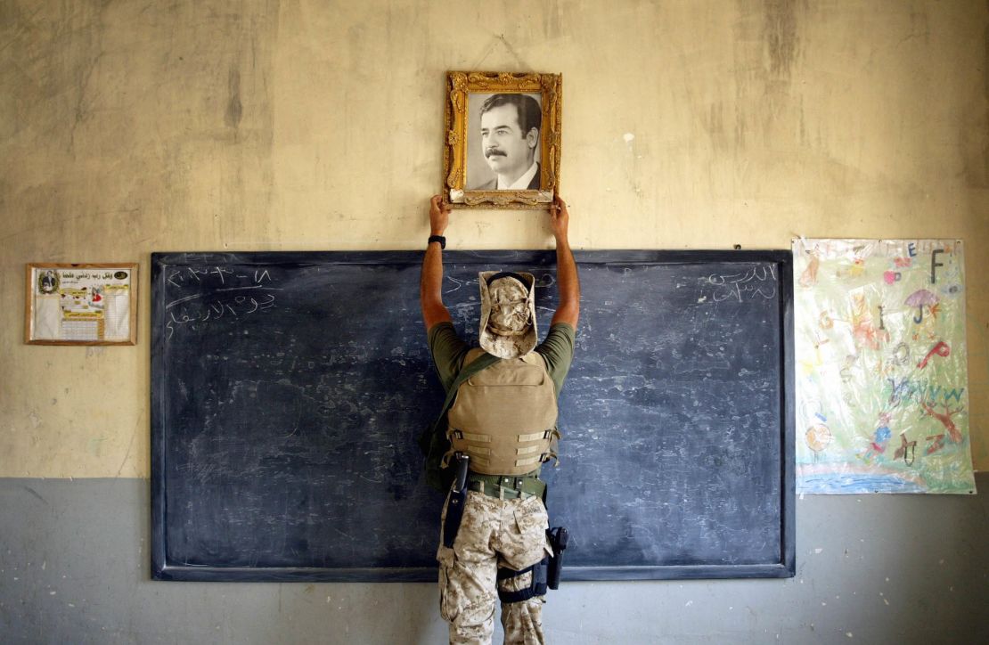 AL-KUT, IRAQ  APRIL 16:  A U.S. Marine pulls down a picture of Saddam Hussein at a school April 16, 2003 in Al-Kut, Iraq. A combination team of Marines, Army and Special Forces went to schools and other facilities in Al-Kut looking for weapons caches and unexploded bombs in preparation for removing and neutralizing them.