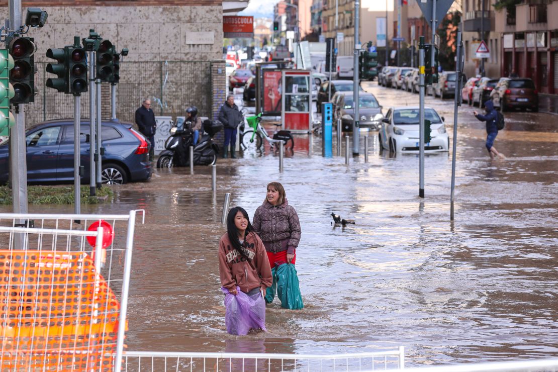 MILAN, ITALY - OCTOBER 31: Two women are seen stuck in a flooded intersection in Milan after a violent storm hit the city on October 31, 2023 in Milan, Italy. The extreme weather is estimated to have caused damage of over €100 million (£85m) across northern regions of Italy. (Photo by Vasile Mihai-Antonio/Getty Images)