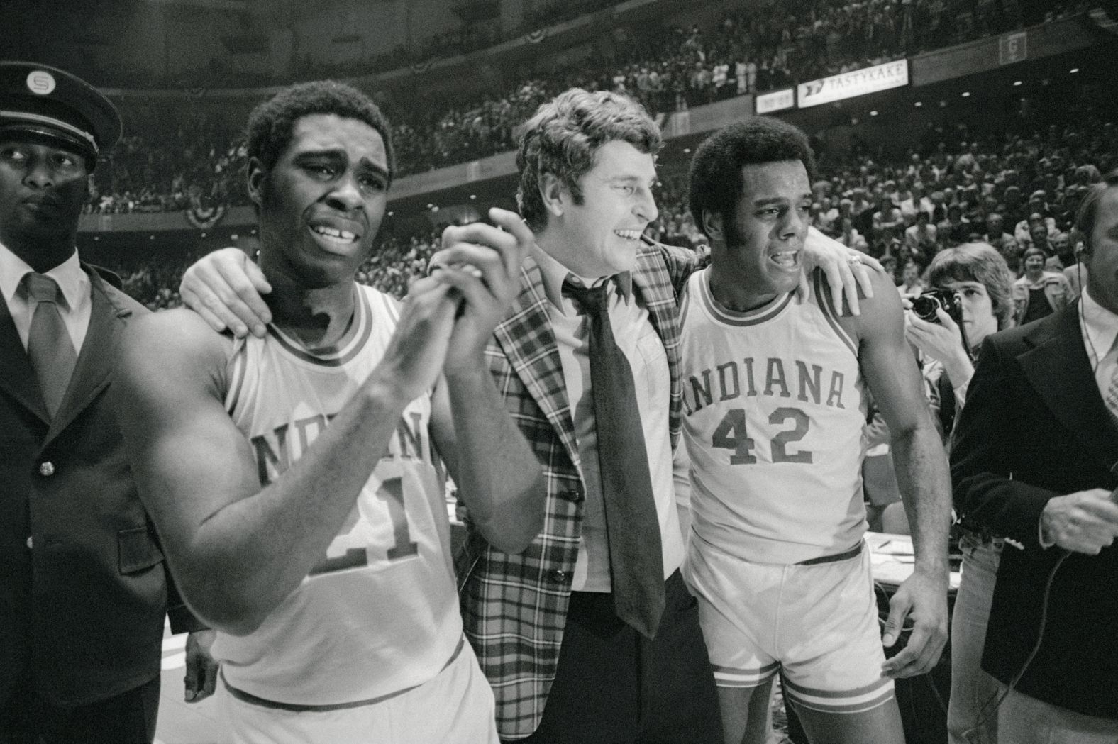 Knight is walked off the court by a tearful Quinn Buckner, left, and Scott May after the Hoosiers won the NCAA championship in 1976.
