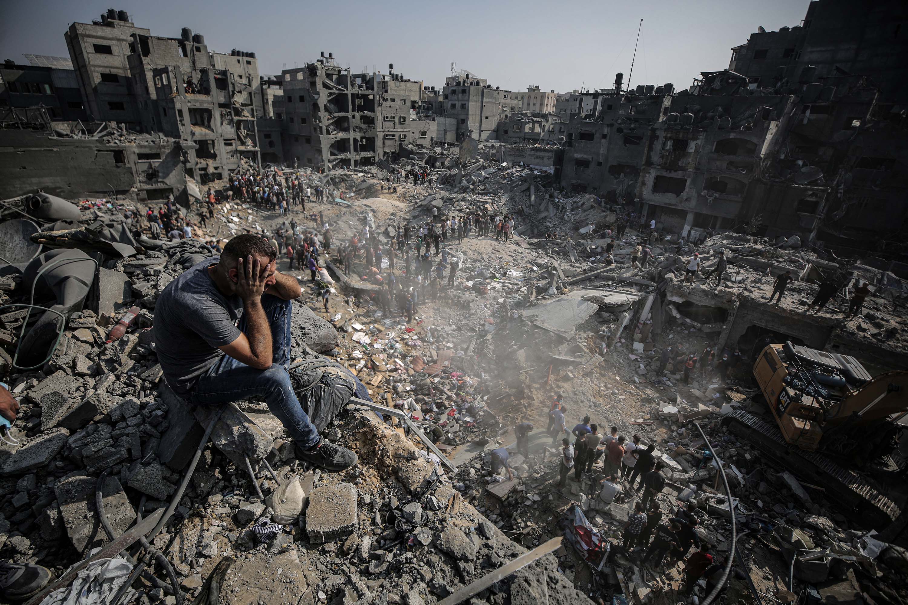 A man sits on debris as Palestinians conduct a search and rescue operation after the second bombardment to the Jabalya refugee camp in Gaza City, on Wednesday, November 1.
