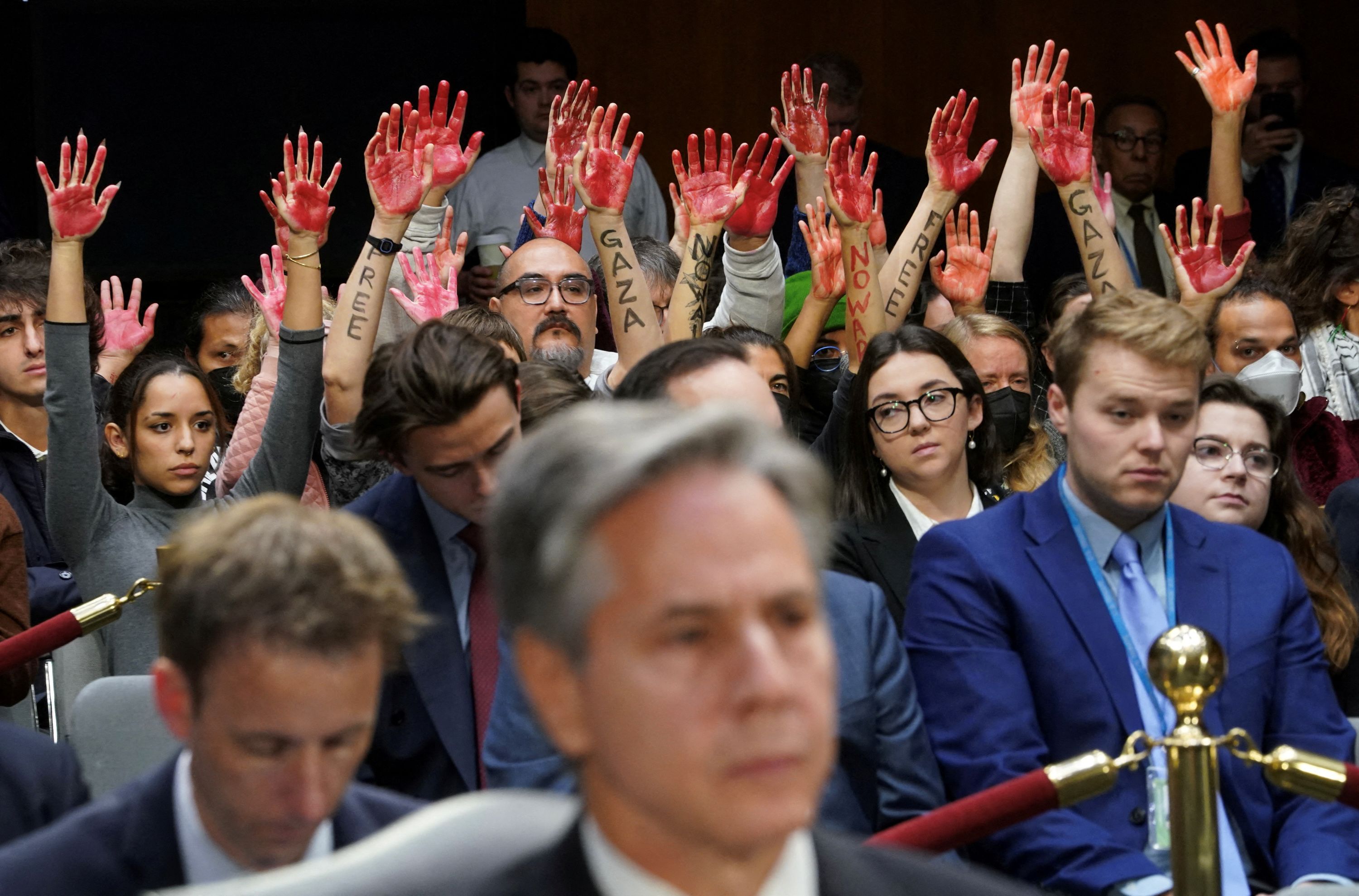 Anti-war protesters raise their 'bloody' hands behind US Secretary of State Antony Blinken during a Senate Appropriations Committee hearing on President Biden's $106 billion national security supplemental funding request on Capitol Hill in Washington, DC, on Tuesday, October 31.