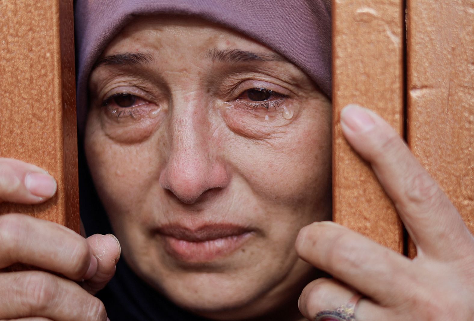 A woman looks from behind a gate at the bodies of Palestinians killed by Israeli strikes at a hospital in Khan Younis, Gaza, on Thursday, October 26.