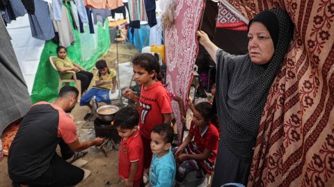A displaced Palestinian elderly woman stands at the door of her tent with her grandchildren next to her, inside tents in the Japanese neighborhood in the city of Khan Yunis, on October 29, 2023. (Loay Ayyoub for The Washington Post via Getty Images)