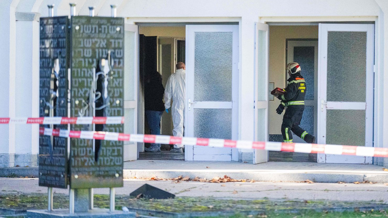 This photo taken on November 1, 2023 shows a firefighter and forensic police at the entrance of the ceremony hall at the Jewish part of the Central Cemetery in Vienna, Austria, after a fire damaged the hall. Austrian police on November 1 were investigating a fire that damaged a hall at the Jewish part of the Vienna cemetery, with politicians condemning anti-Semitic violence. Cities in Europe have seen a spike in anti-Semitic attacks in response to the Israel-Hamas conflict. In the night from October 31 to November 1, a fire broke out at the Jewish part of the Vienna cemetery, damaging a ceremony hall, officers said. (Photo by GEORG HOCHMUTH / APA / AFP) / Austria OUT (Photo by GEORG HOCHMUTH/APA/AFP via Getty Images)