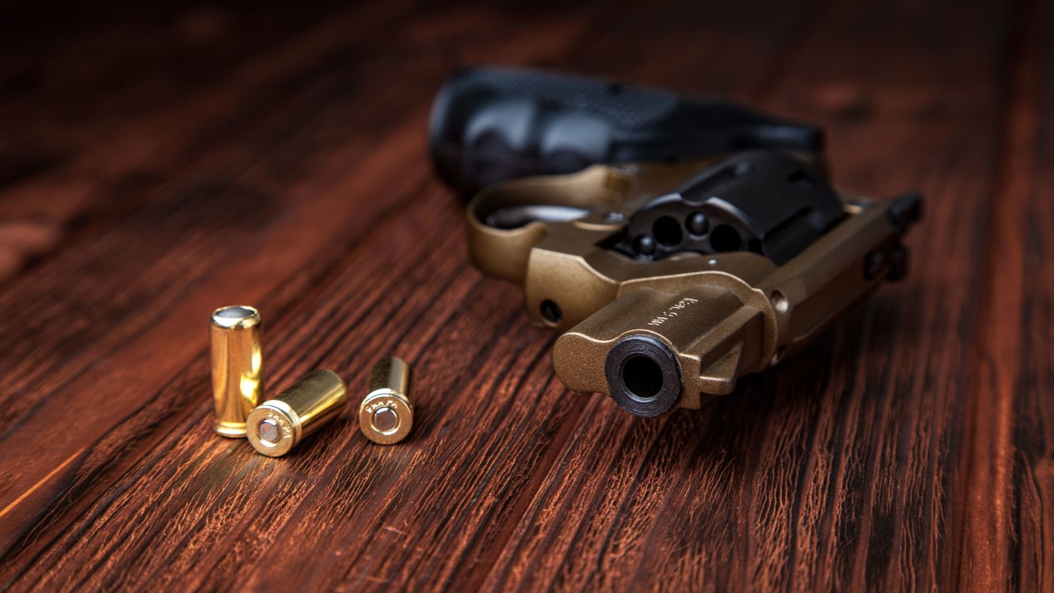 pistol and cartridges on a brown wooden background