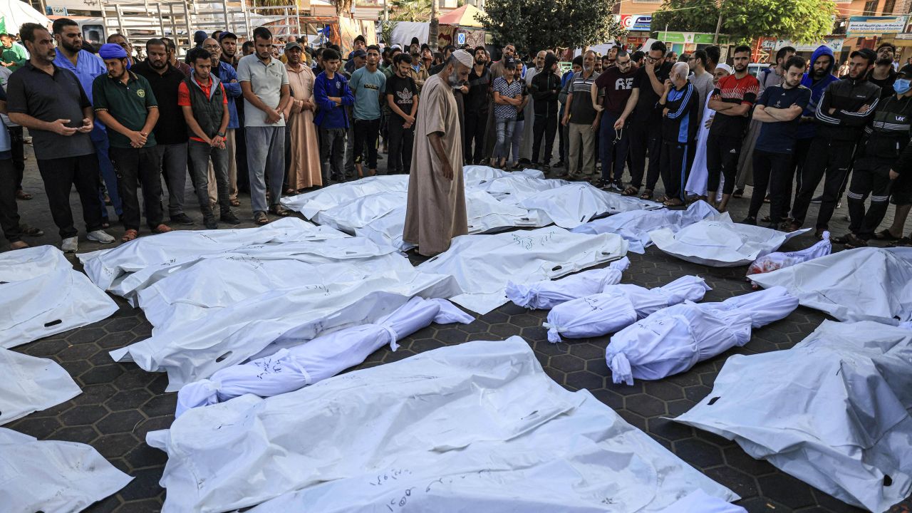 TOPSHOT - A man walks between the bodies wrapped in shrouds of those killed in Israeli bombardment in Deir Balah in the central Gaza Strip, at the Shuhada Al-Aqsa hospital in the same city on November 6, 2023, amid the ongoing battles between Israel and the Palestinian group Hamas. (Photo by MAHMUD HAMS / AFP) (Photo by MAHMUD HAMS/AFP via Getty Images)