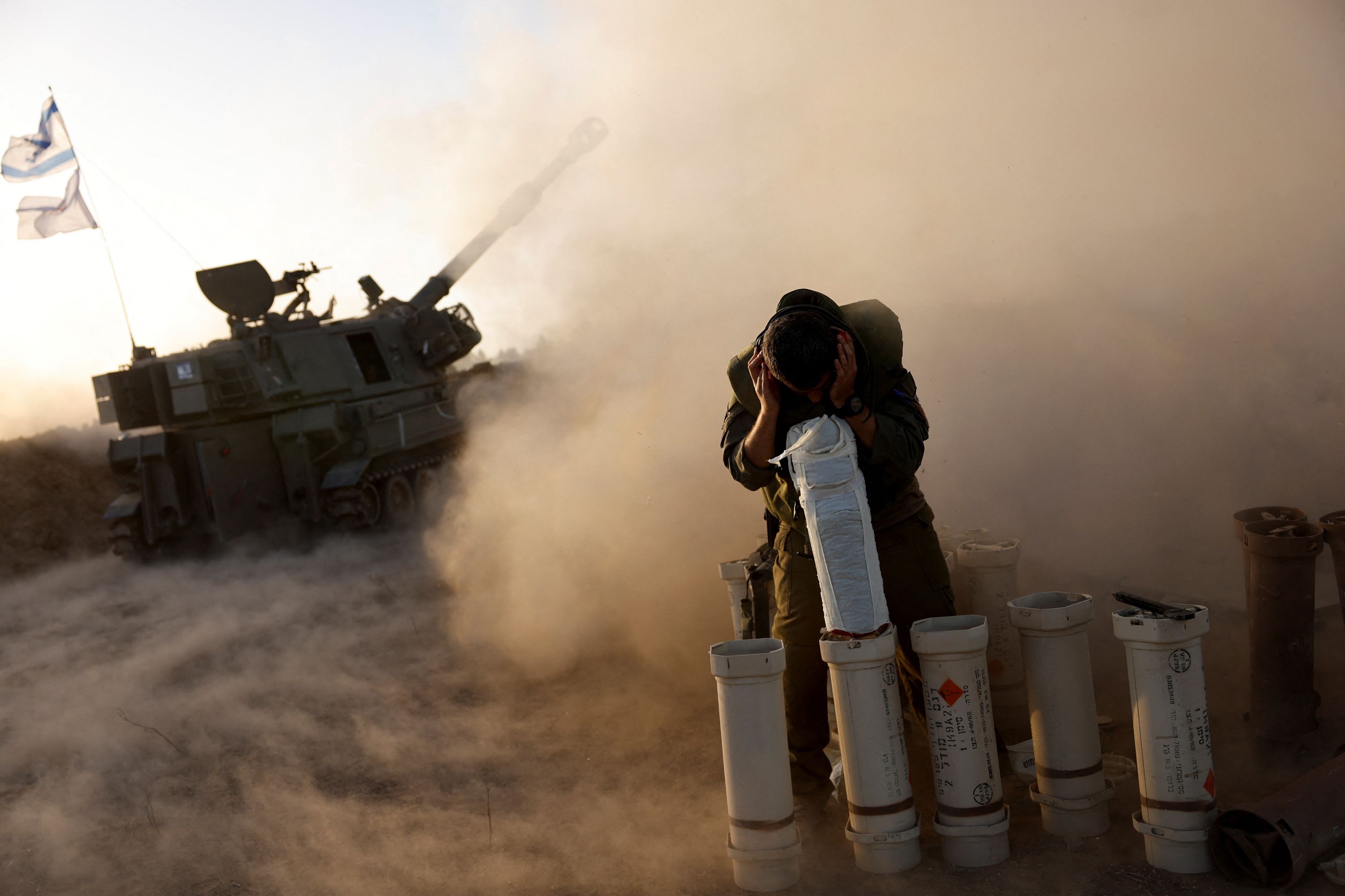 A soldier takes cover as an artillery unit fires from an undisclosed location near the Israel-Gaza border on November 6.