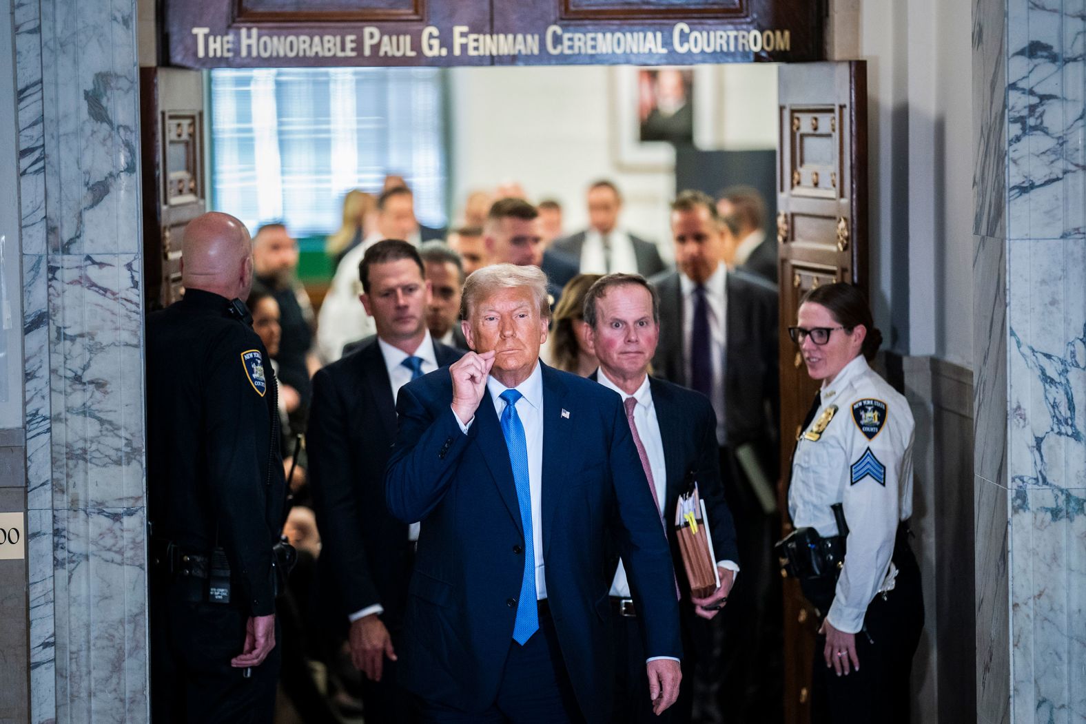 Trump gestures a zipped lip in front of reporters as he walks out of a New York courtroom during a break in his civil fraud trial on November 6.