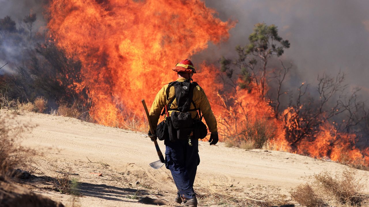 TOPSHOT - A firefighter walks toward flames as the Highland Fire burns in Aguana, California, on October 31, 2023. Thousands of people were being told to flee a wildfire spreading in southern California on October 31, as strong winds fanned the flames.Around 5,700 people were urged to leave areas threatened by the blaze, which erupted on October 30 around lunchtime and had engulfed 2,200 acres (900 hectares) by the following morning. (Photo by DAVID SWANSON / AFP) (Photo by DAVID SWANSON/AFP via Getty Images)