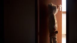 Child standing in a darkened doorway, opening a door to the light - stock photo