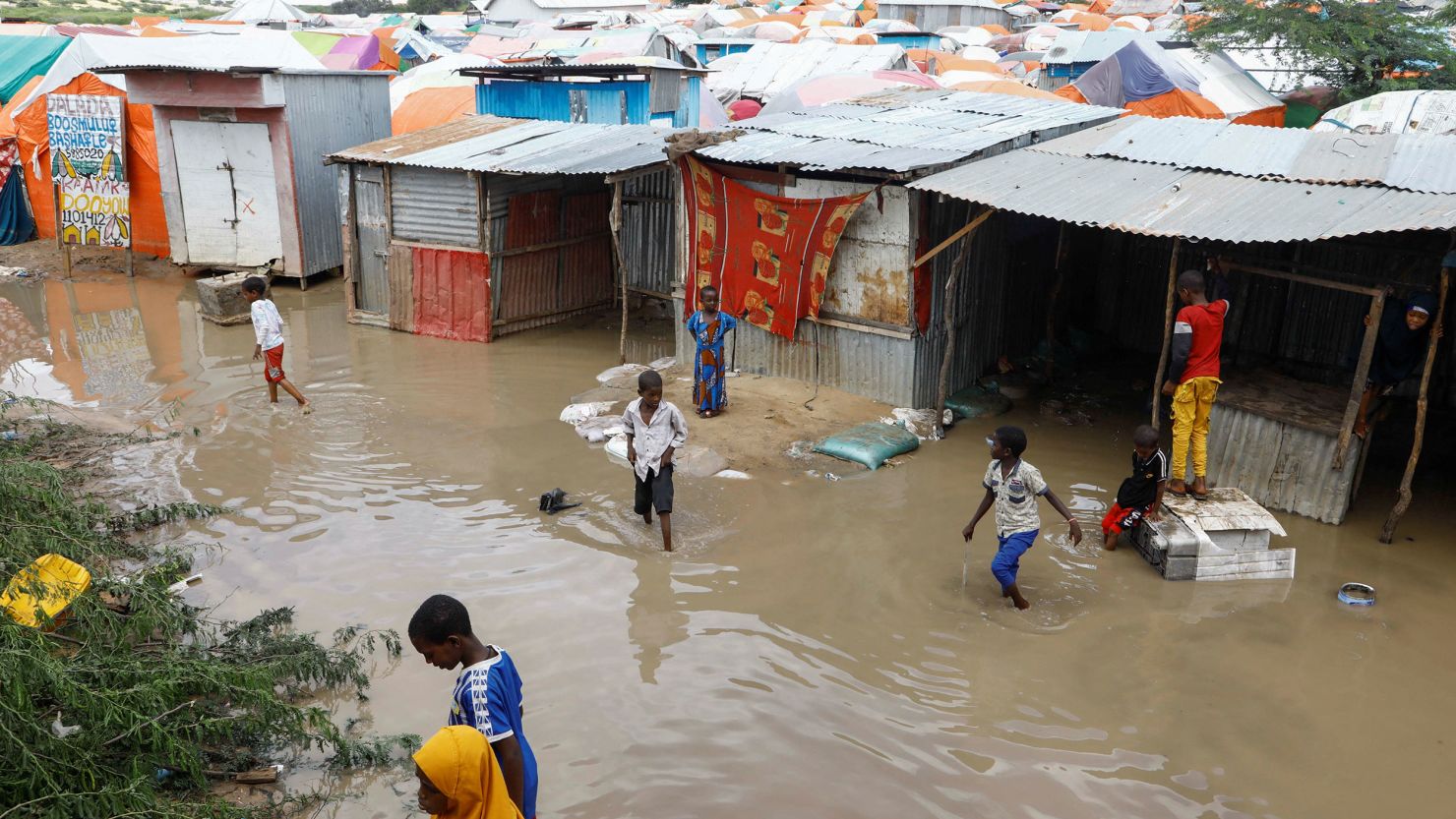 Internally displaced Somali children wade through flood waters outside their makeshift shelters following heavy rains at the Al Hidaya camp for the internally displaced people on the outskirts of Mogadishu, Somalia November 6, 2023 REUTERS/Feisal Omar