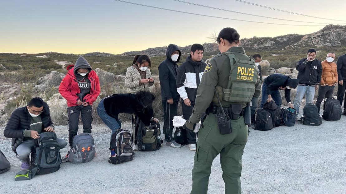 U.S. Border Patrol agent talking to migrants as they await processing at the U.S. / Mexico border in San Diego County.