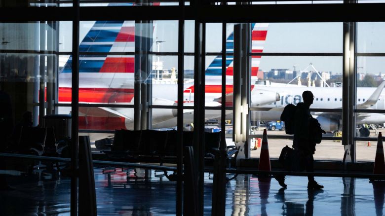 American Airlines airplanes are seen past a traveler walking through Ronald Reagan Washington National Airport in Arlington, Virginia, on November 22, 2022, ahead of the upcoming Thanksgiving holiday. (Photo by SAUL LOEB / AFP) (Photo by SAUL LOEB/AFP via Getty Images)