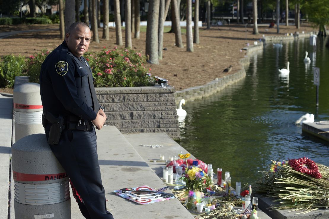 Eatonville Police Department officer Omar Delgado stands next to a makeshift memorial for victims of the Pulse nightclub shooting at Lake Eola Thursday, June 23, 2016, in Orlando, Fla. (Phelan M. Ebenhack via AP)