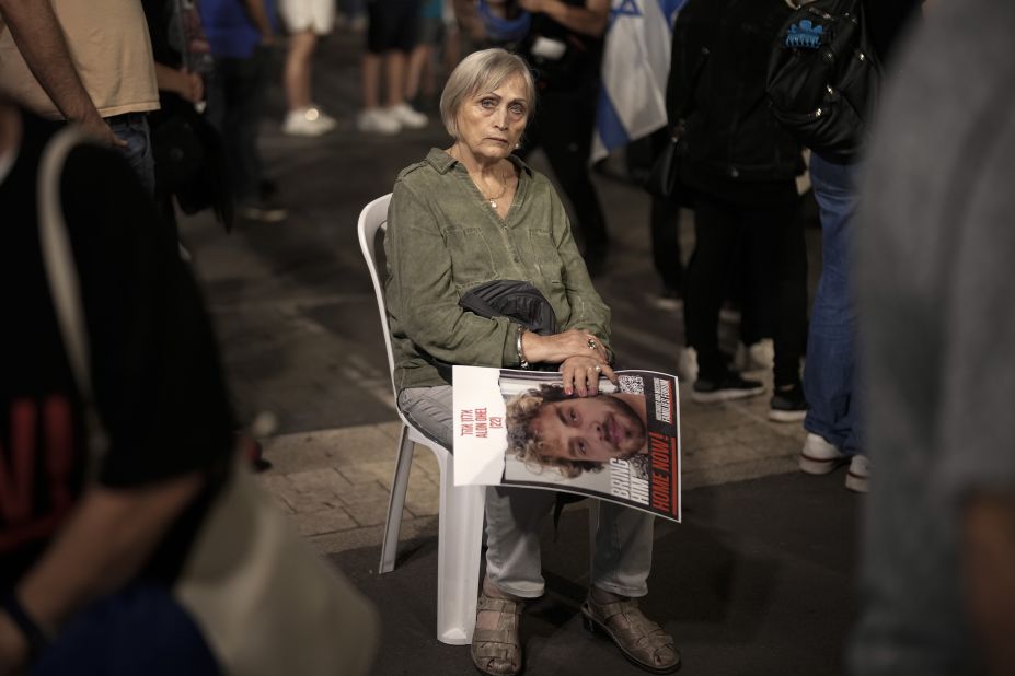On day 35 of hostages being detained by Hamas, a woman holds the image of a hostage while sitting amongst thousands of people and families of kidnapped people taking part in a protest to demand that Israeli Prime Minister Benjamin Netanyahu secures the release of Israeli hostages, on Saturday, November 11, in Tel Aviv, Israel. 