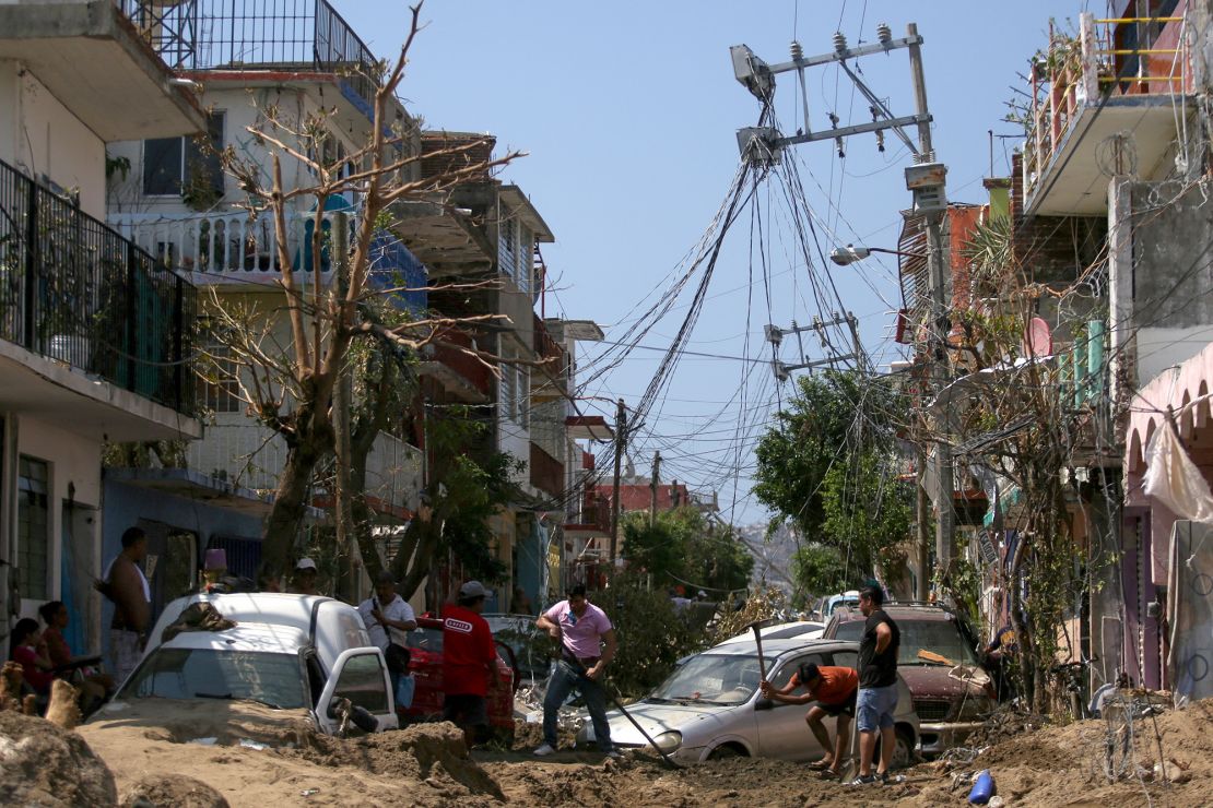 People work to free cars stuck in the mud, in the aftermath of Hurricane Otis, in the Progreso neighbourhood in Acapulco, Mexico, October 30, 2023. REUTERS/Quetzalli Nicte-Ha