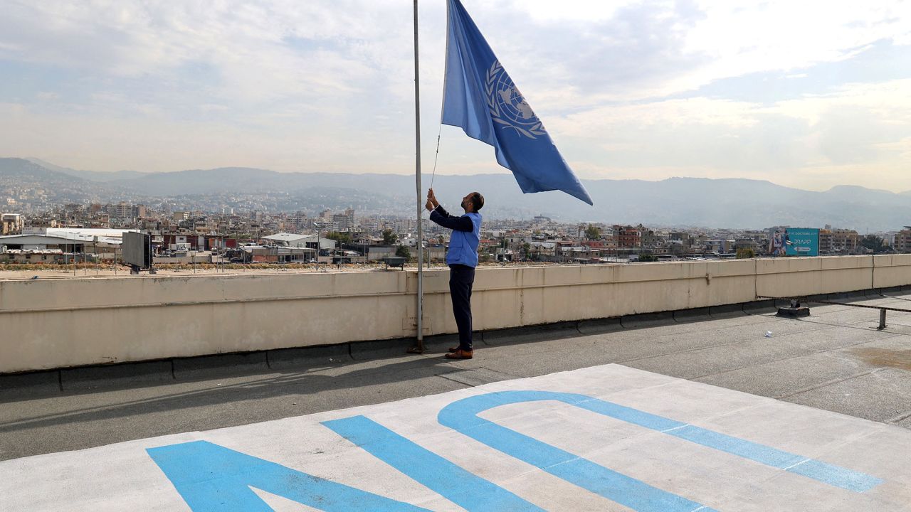 TOPSHOT - An employee at the United Nations Relief and Works Agency (UNRWA) for supporting Palestinians lowers the UN flag on the roof of the organisation's regional offices in the Lebanese capital Beirut on November 13, 2023. Flags flew at half-mast at United Nations compounds across the globe on November 13, as staff observed a minute's silence in memory of colleagues killed in Gaza during the Israel-Hamas conflict. (Photo by ANWAR AMRO / AFP) (Photo by ANWAR AMRO/AFP via Getty Images)