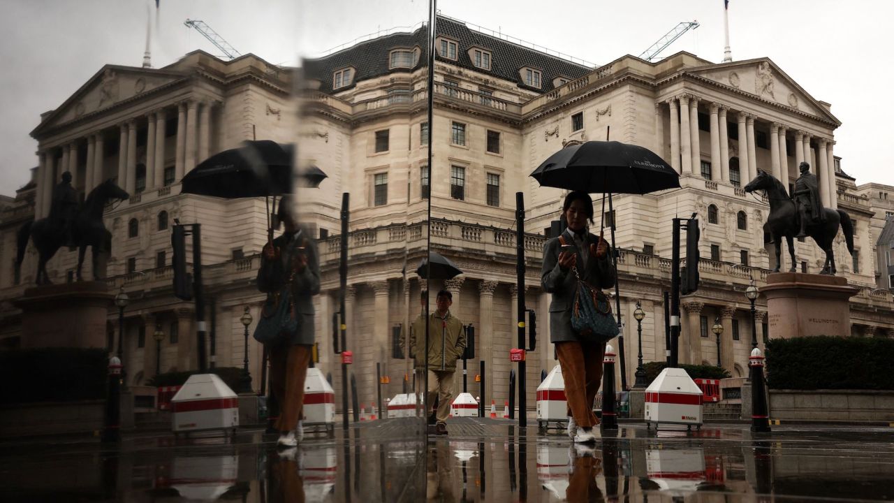 A pedestrian shelters from the rain beneath an umbrella as they walk near the Bank of England in the City of London on November 10, 2023. Britain's economy stagnated in the third quarter, official data showed Friday, weighed down by elevated inflation and interest-rate hikes. (Photo by Daniel LEAL / AFP) (Photo by DANIEL LEAL/AFP via Getty Images)