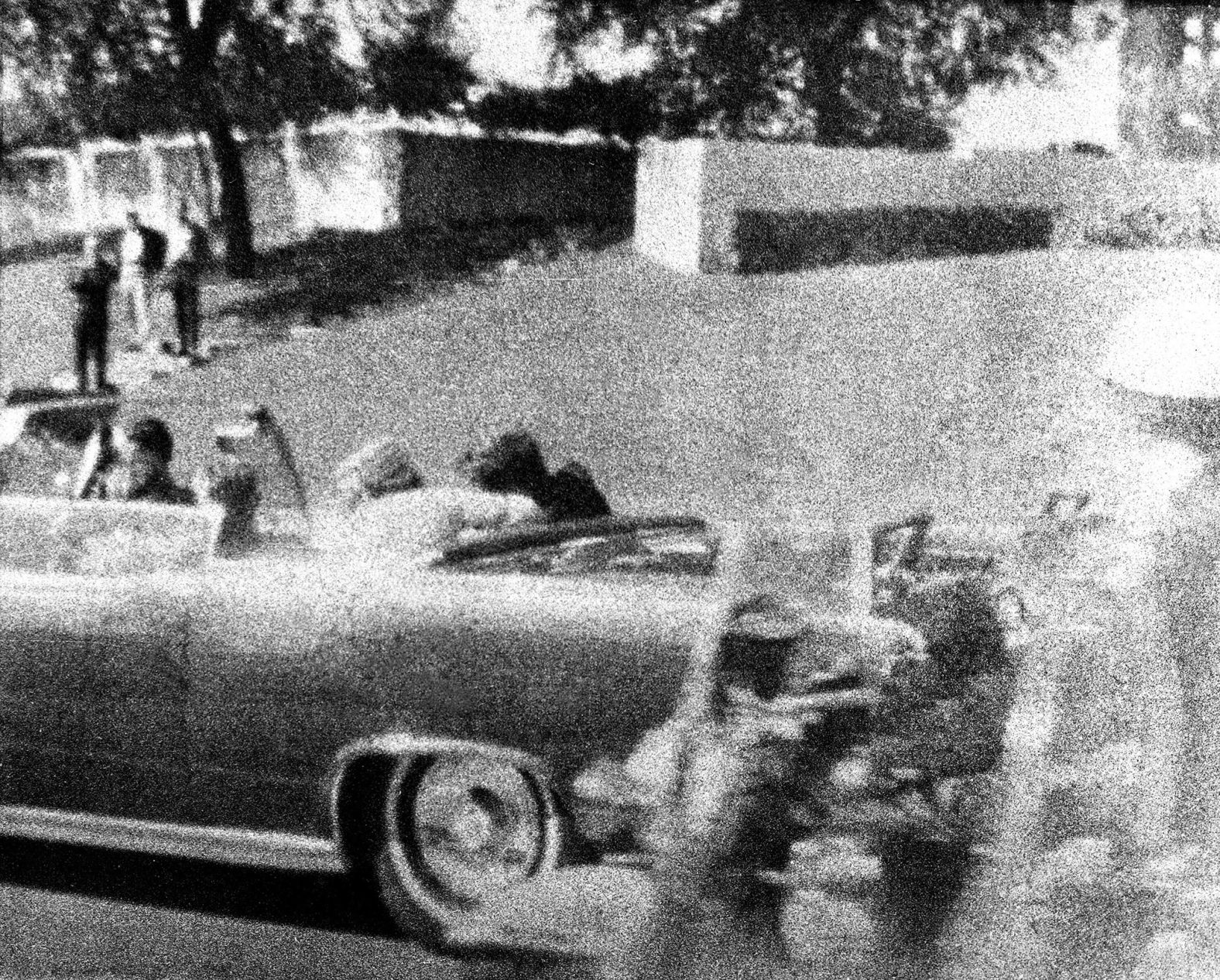 Kennedy slumps against his wife as a bullet strikes him in the head. Wire services reported that three shots were fired as the motorcade passed under the Stemmons Freeway. Two bullets hit the president and one hit the governor.