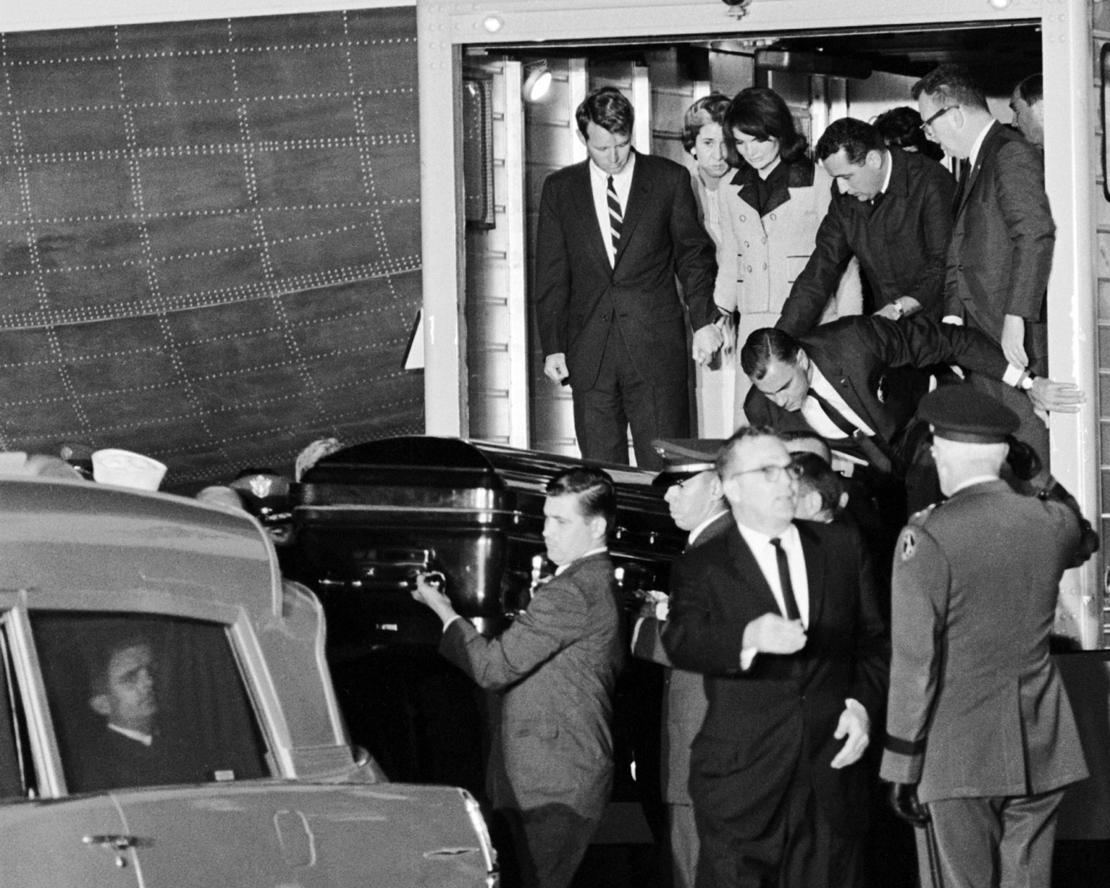 Kennedy's casket is moved from Air Force One to an ambulance upon arrival at Joint Base Andrews Air Force Base. Jacqueline Kennedy is holding hands with her brother-in-law Robert Kennedy.
