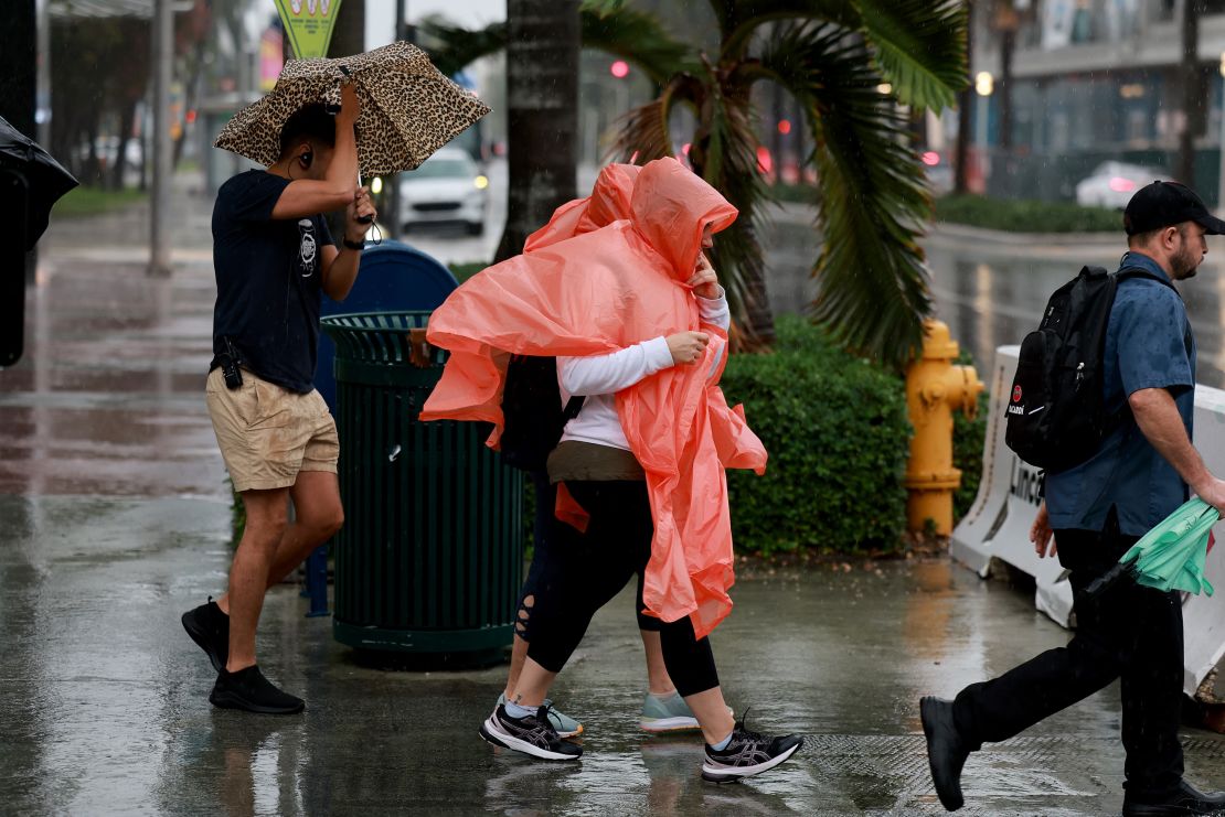 MIAMI BEACH, FLORIDA - NOVEMBER 15: Pedestrians try to stay dry as rain inundates the area on November 15, 2023 in Miami Beach, Florida.  A weather system slowly passing through South Florida is leaving Miami-Dade soaked and causing concern for potential flooding. (Photo by Joe Raedle/Getty Images)