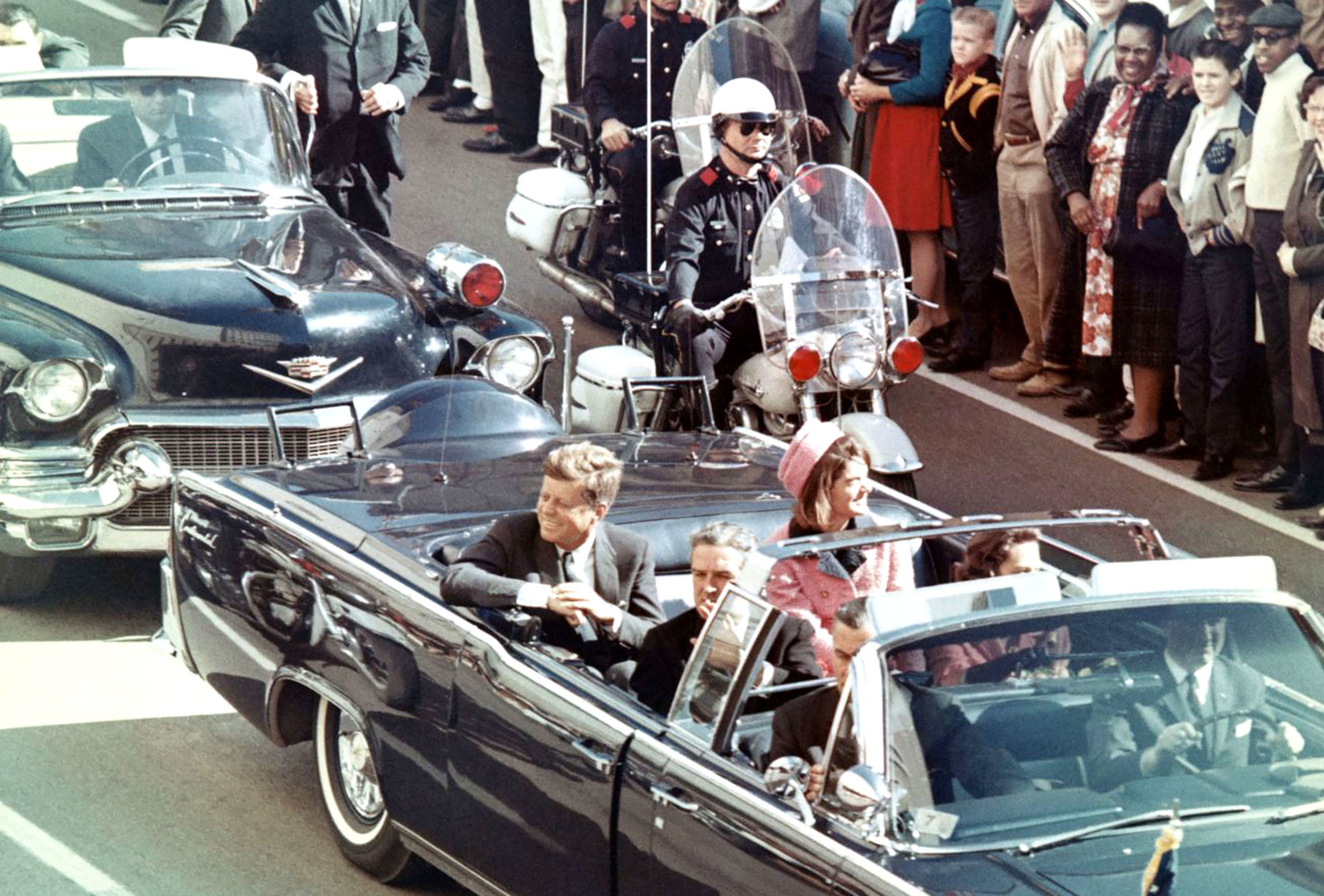 President John F. Kennedy rides in the back seat with his wife, Jacqueline, as his motorcade drives toward Dealey Plaza in Dallas on November 22, 1963.