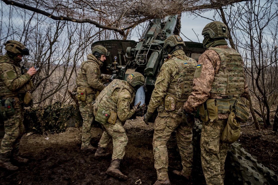 Ukrainian servicemen load a shell into a Msta-B howitzer to fire towards Russian positions.