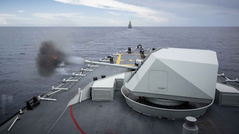 HMCS OTTAWA fires its main gun towards the Hammerhead remote training target as USS RAFAEL PERALTA and HMAS BRISBANE sail in formation during a Surface Fire Exercise (SURFIREX) during INDO-PACIFIC DEPLOYMENT in the South China Sea on 26 October 2023.