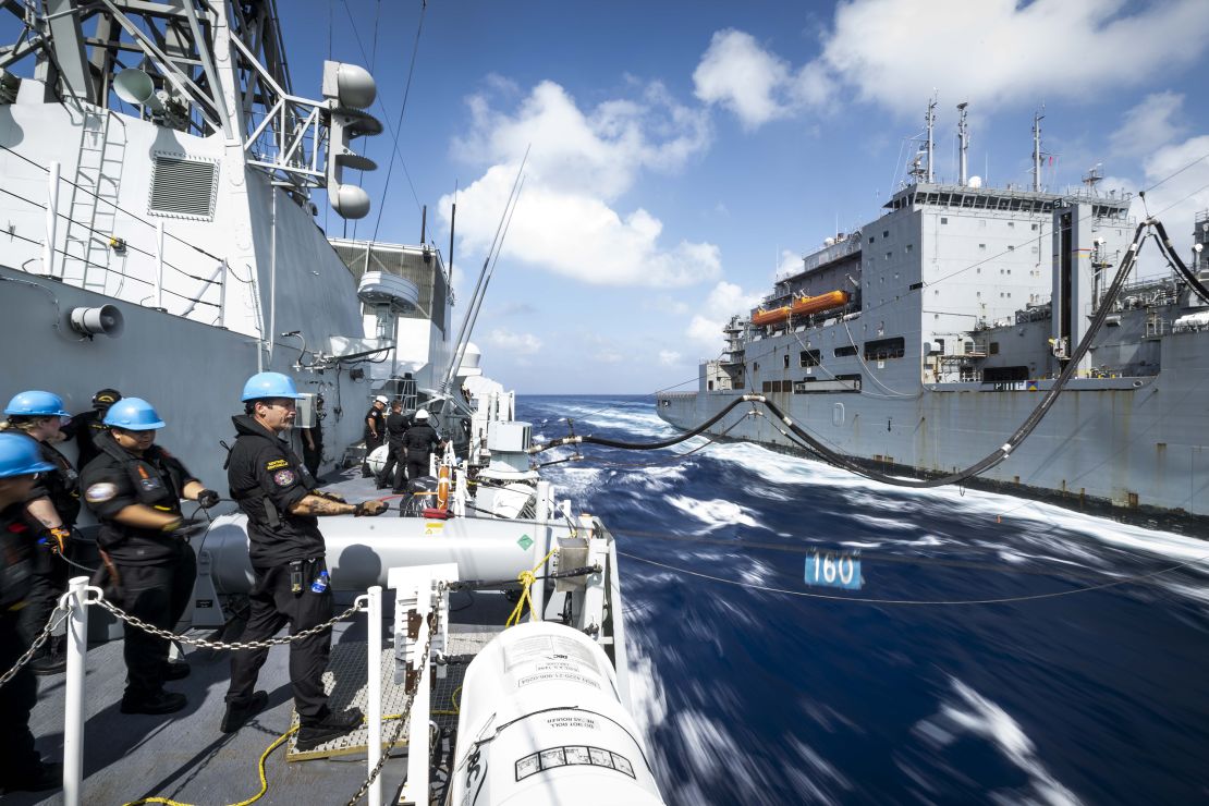 Crew on board HMCS Ottawa's hold a distance line from USNS Wally Shirra as the two ships conduct a replenishment at sea mission in the South China Sea on 30 October 2023.