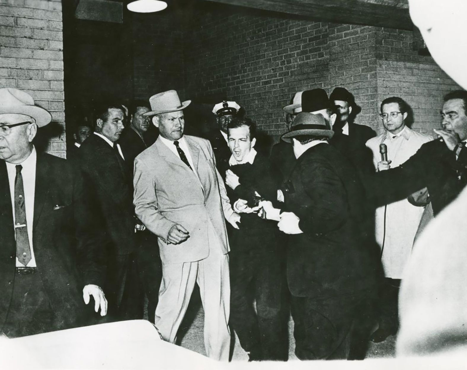 Lee Harvey Oswald reacts as Dallas night club owner Jack Ruby shoots at him in a corridor of the Dallas police headquarters.