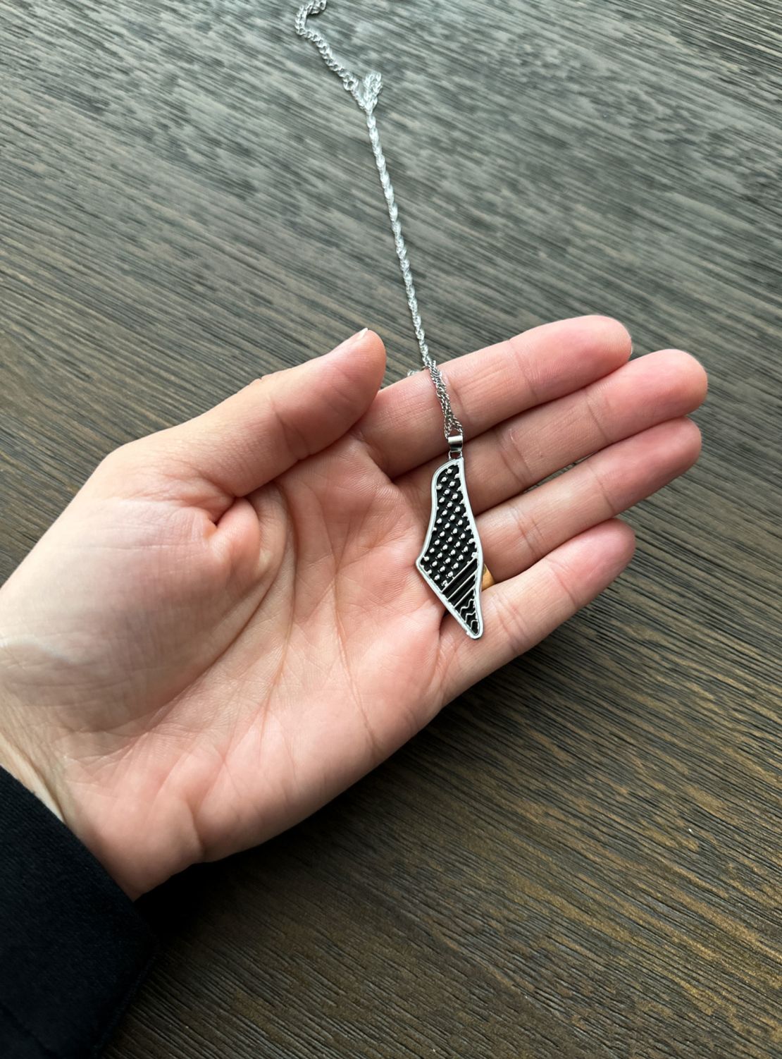 Mona displays a necklace of Palestine on November 9, 2023. She wears the necklace under her clothes out of fear.