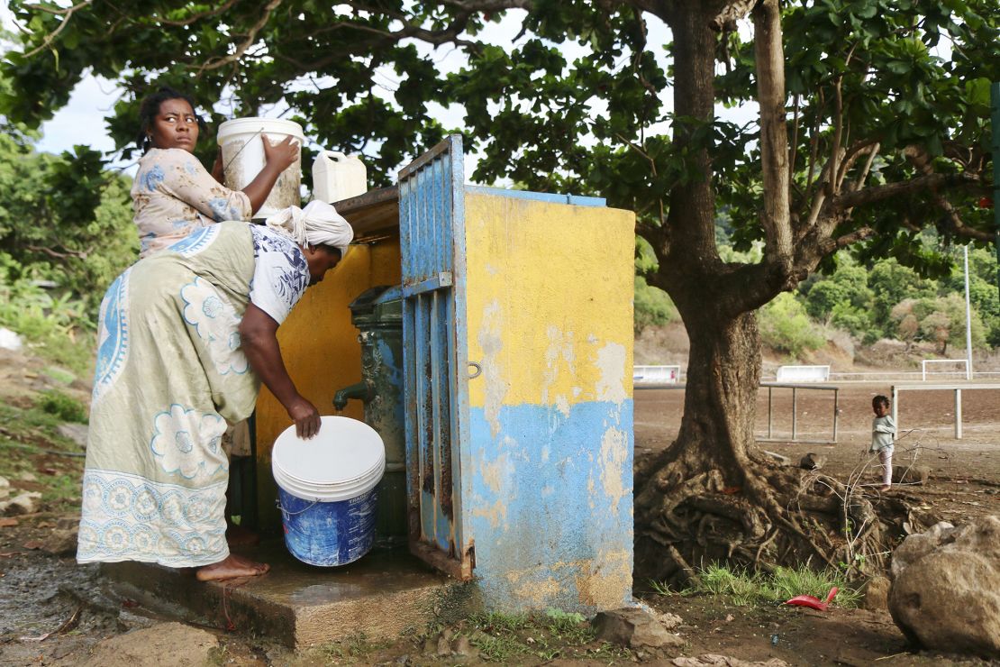 Women fill up buckets with water in the district of M'tsamoudou, near Bandrele, on the French Indian Ocean territory of Mayotte, Thursday, Oct. 12, 2023. Water taps flow just one day out of three because of a drawn-out drought compounded by years of water mismanagement. (AP Photo/Gregoire Merot)
