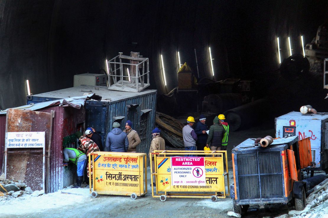 Police and officials stand at the entrance of the under construction road tunnel tha collapsed in Uttarkashi district of India's Uttarakhand state on November 17, 2023, as resuce operations continue to reach the 40 men trapped inside the tunnel. Indian rescuers said on November 17 they had drilled less than halfway through the debris to reach 40 men trapped in a collapsed tunnel for nearly a week. (Photo by AFP) (Photo by -/AFP via Getty Images)