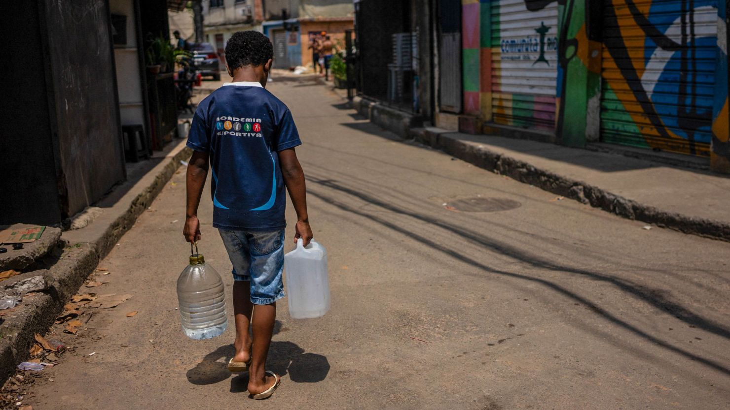 A resident of Rocinha slum carries water collected from a natural spring during a heat wave in Rio de Janeiro, Brazil, on November 17, 2023. The heatwave that has been affecting much of Brazil for several days continues, with stifling temperatures in cities like Rio de Janeiro, where the heat index reached a record of 58.5 °C (137.3 degrees Fahrenheit), as reported by authorities. (Photo by Tercio TEIXEIRA / AFP) (Photo by TERCIO TEIXEIRA/AFP via Getty Images)