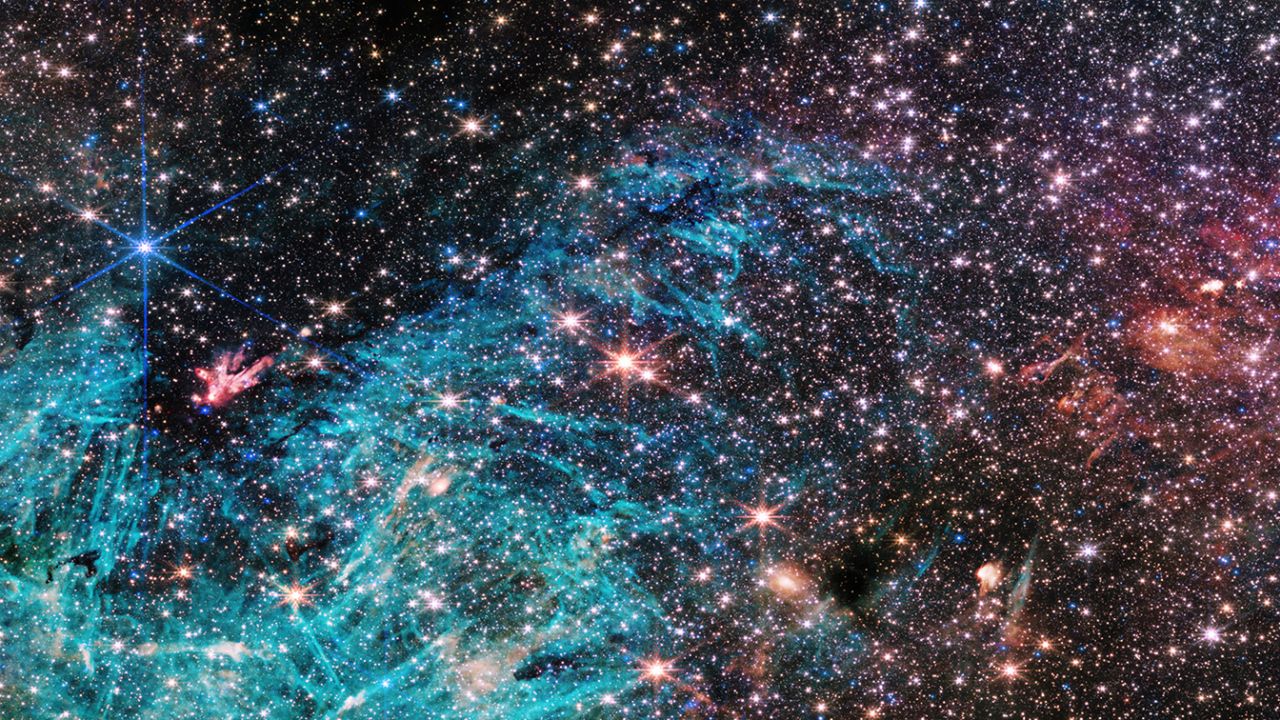 There are approximately 500,000 stars in this image of the Sagittarius C region of the Milky Way. The bright cyan area contains emissions from ionized hydrogen.