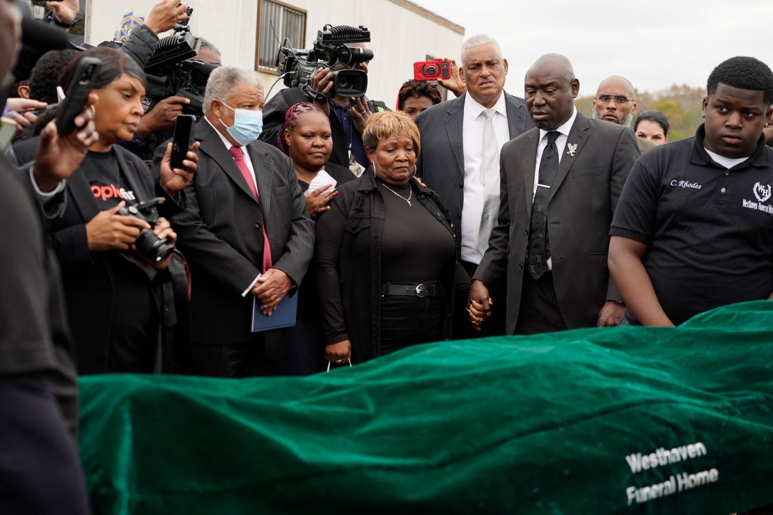 FILE - Surrounded by family members and holding hands with civil rights attorney Ben Crump, center right, Bettersten Wade, center, mother of Dexter Wade, a 37-year-old man who died after being hit by a Jackson, Miss., police SUV driven by an off-duty officer, watches her son's body transferred to a mortuary transport in Raymond, Miss. Nov. 13, 2023. An independent pathologist says the deceased Mississippi man had a wallet in the front pocket of the jeans he was buried in that contained his home address. Crump says the finding came from Dr. Frank Peretti's autopsy report. Peretti was hired to perform an autopsy after Wade's body was exhumed. (AP Photo/Rogelio V. Solis, file)