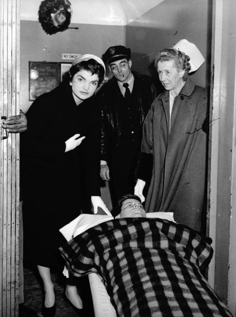 Kennedy, lying on a stretcher, leaves a hospital in New York after surgery on his spine in December 1954. Helping him is his wife, Jacqueline, and nurse Mary Virtue.