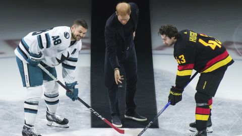 Prince Harry, center, Duke of Sussex, drops the puck for San Jose Sharks' Tomas Hertl, left, and Vancouver Canucks' Quinn Hughes, right, during a ceremonial face off prior to an NHL hockey game in Vancouver, British Columbia, Monday, Nov. 20, 2023. (Darryl Dyck/The Canadian Press via AP)
