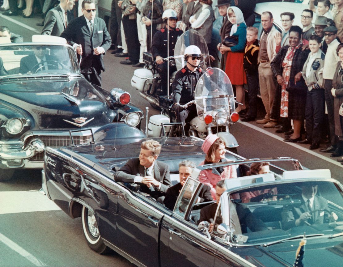 President John F. Kennedy rides in the back seat with his wife, Jacqueline, as his motorcade drives toward Dealey Plaza in Dallas on November 22, 1963. He was shot minutes later by Lee Harvey Oswald, a single gunman acting alone in the Texas School Book Depository.