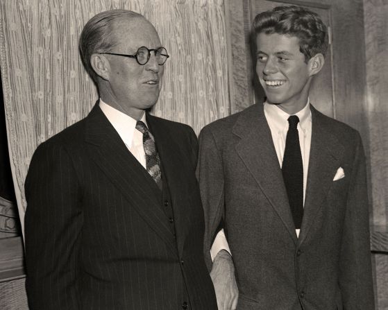 Kennedy links arms with his father aboard the Queen Mary ocean liner as they arrive in New York for the Christmas holidays in December 1938. At the time, the elder Kennedy was the US ambassador to the United Kingdom.