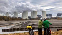 Cyclists look towards cooling towers at the Jaenschwalde lignite coal-fired power plant, in Peitz, Germany, on Tuesday, Nov. 7, 2023. German Economy Minister Robert Habeck pushed back against doubts that Europe's largest economy can phase out coal by 2030 after ramping up its use in the aftermath of the energy crisis. Photographer: Krisztian Bocsi/Bloomberg via Getty Images