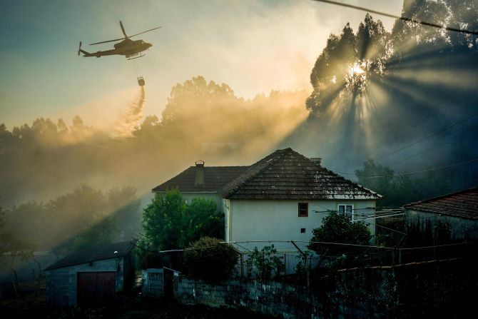 This photo by Adrián Irago also captures the forest fires in Spain, as a helicopter unloads water. 