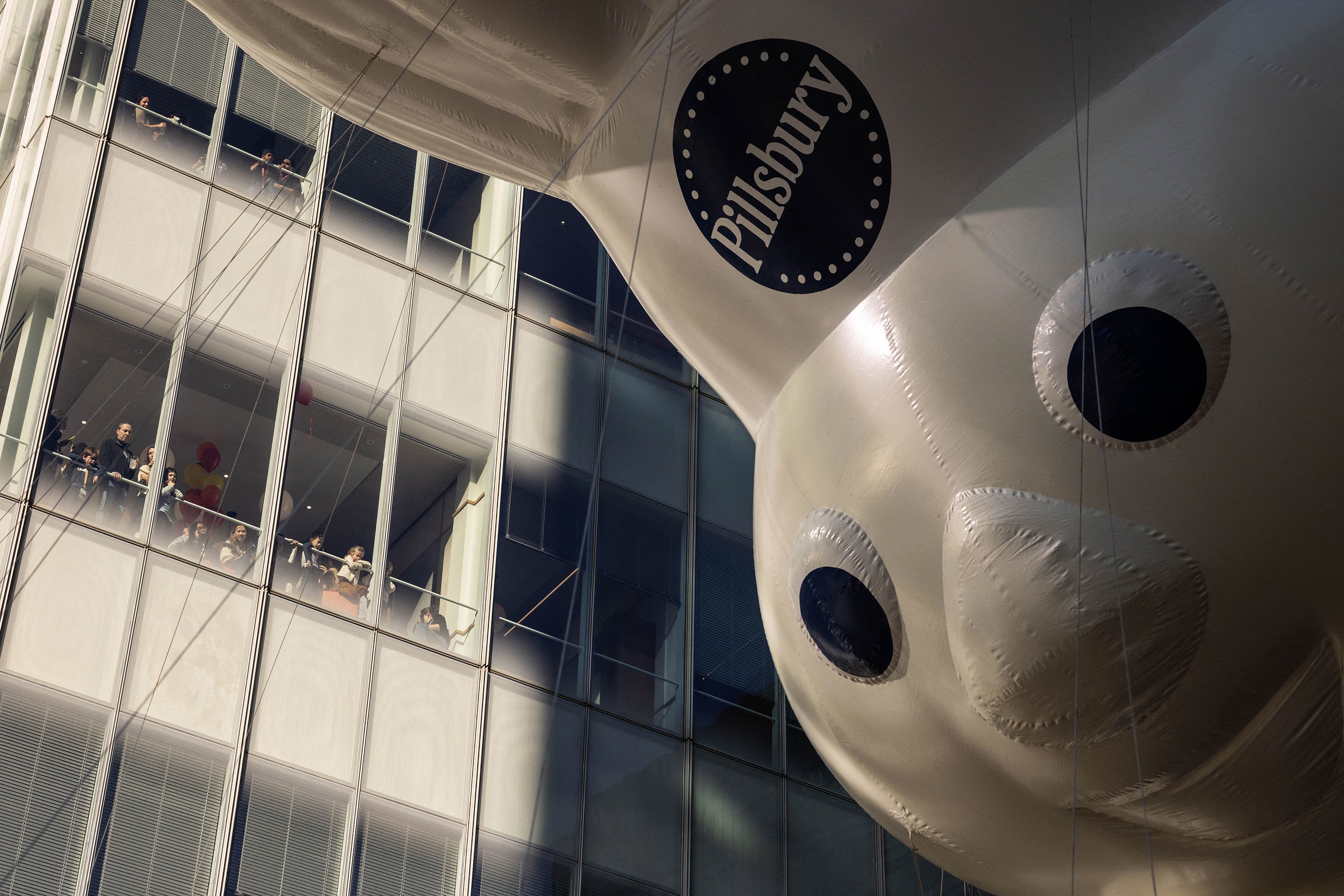 People in New York watch the Pillsbury Doughboy balloon during the annual Macy's Thanksgiving Day Parade on Thursday, November 23.