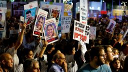 People hold placards as they await news of hostages expected to be released by Hamas, amid a hostages-prisoners swap deal between Hamas and Israel, in Tel Aviv, Israel, November 25, 2023.
