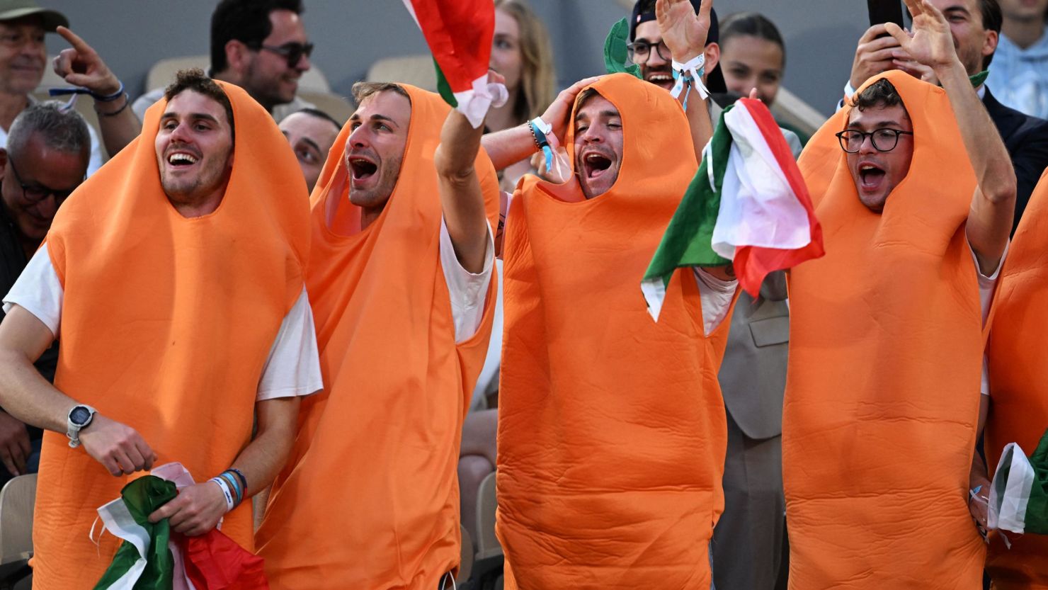 TOPSHOT - Fans of Italy's Jannik Sinner, dressed as carrots, gestures during his men's singles match against France's Alexandre Muller on day two of the Roland-Garros Open tennis tournament at the Court Philippe-Chatrier in Paris on May 29, 2023. (Photo by Emmanuel DUNAND / AFP) (Photo by EMMANUEL DUNAND/AFP via Getty Images)